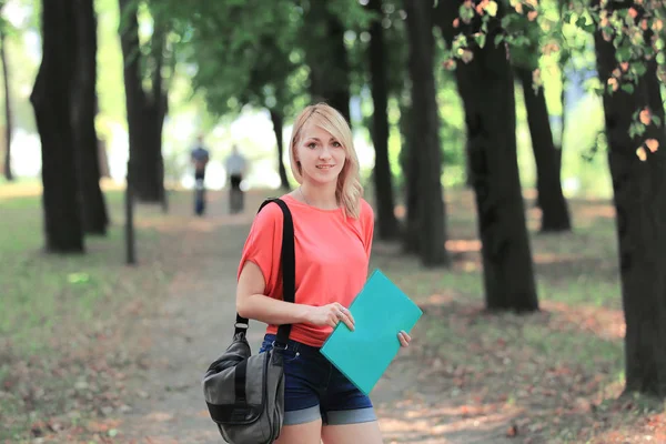 Framgångsrik kvinnlig student med en väska och ett Urklipp på bakgrunden av parken — Stockfoto
