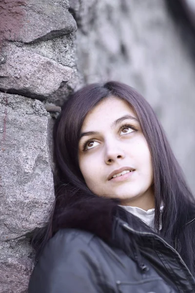 Porträtt av en ung kvinna mot en stenmur — Stockfoto