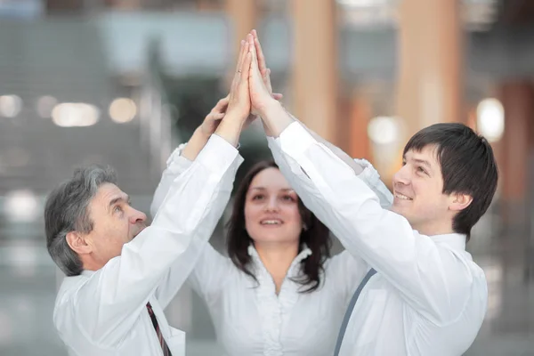 Members of the business team giving each other a high-five,standing in the office — Stock Photo, Image