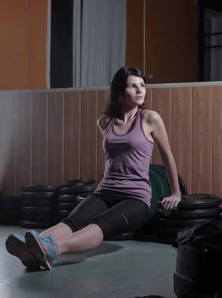 Sportieve vrouw zittend op de vloer in het fitnesscenter — Stockfoto