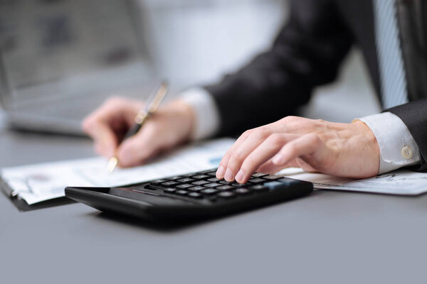 Закрывай. бизнесмен использует калькулятор, чтобы проверить правильность расчетов
