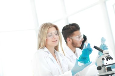 Yakın çekim. Genç bilim adamları sıvı üzerinde deney yapıyorlar.