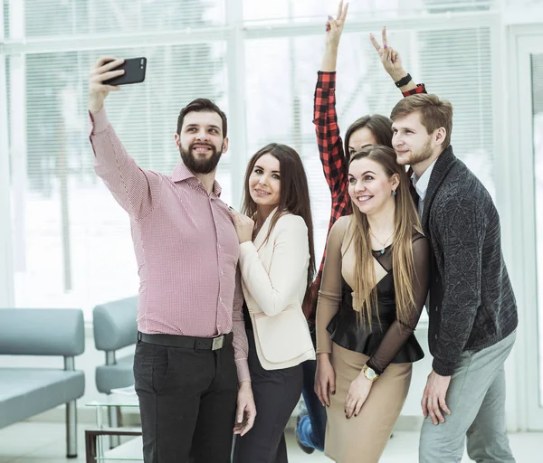 Amigable equipo de negocios tomando una selfie mientras está de pie cerca de la ventana en la oficina — Foto de Stock