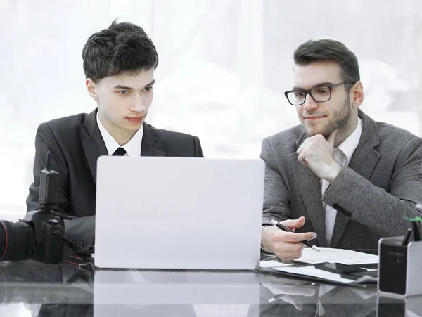 qualified photographers discuss photos to upload files on a laptop .