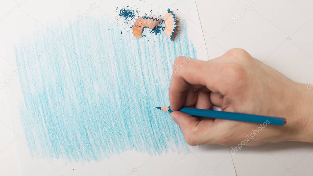 closeup.the artist drawing with a blue pencil on a white sheet