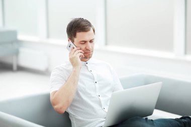 Otel lobisinde otururken telefonla konuşan ciddi adam