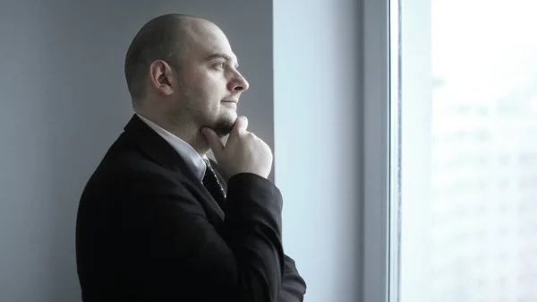 De cerca. pensativo hombre de negocios mirando por la ventana de la oficina —  Fotos de Stock