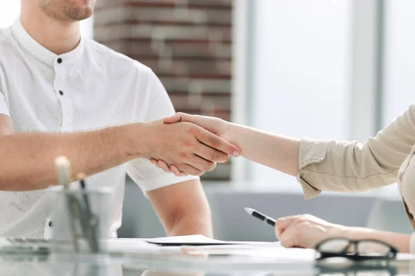 Hombre de negocios y mujer de negocios estrechando la mano mientras se sienta en el escritorio . —  Fotos de Stock