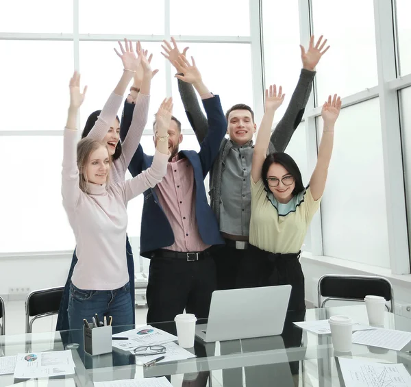 Felice business team in piedi vicino al desktop con le mani in alto — Foto Stock
