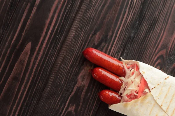 Spicy sausages in pita bread on wooden background.photo with co — Stock Photo, Image