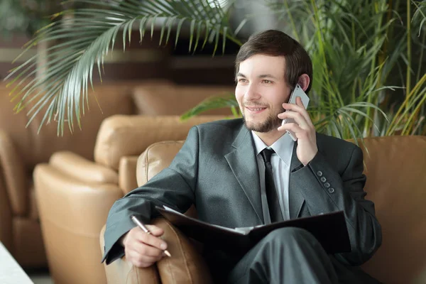 Close up.Businessman sentado em um centro de negócios lendo documentos enquanto tem uma chamada telefônica — Fotografia de Stock