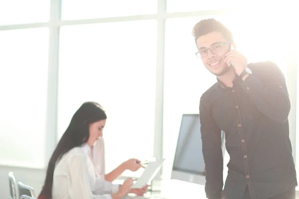 Jungunternehmer spricht im Büro auf seinem Smartphone — Stockfoto