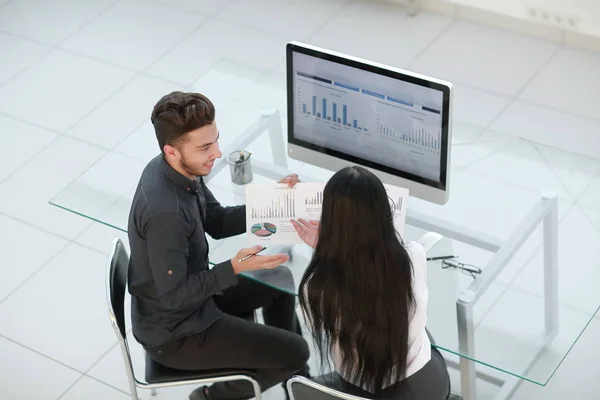 Két alkalmazott pénzügyi adatokat tárgyal egy irodai asztalnál ülve — Stock Fotó