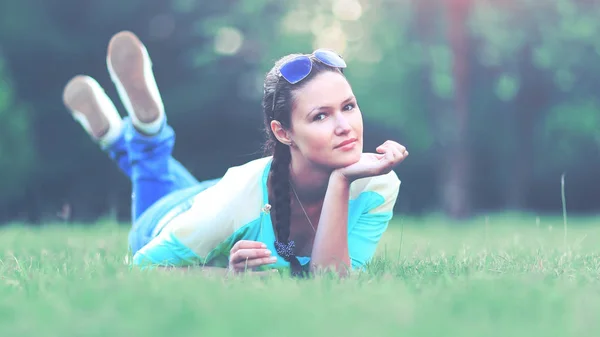 Mladá hezká žena ležící na trávě při západu slunce — Stock fotografie