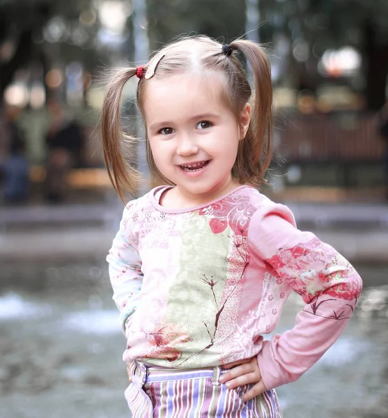 Retrato de niña feliz cerca de la fuente en el parque de la ciudad — Foto de Stock