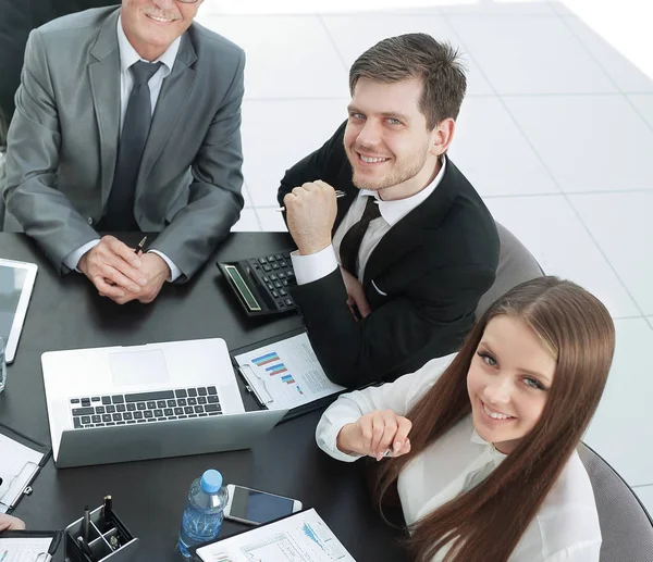 Business team zit aan Bureau en camera kijken. — Stockfoto