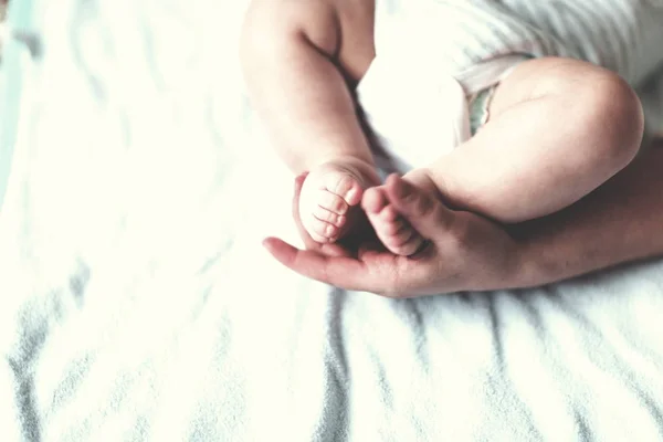 De voeten van de baby in handen van de moeder. Moeder en haar kind — Stockfoto