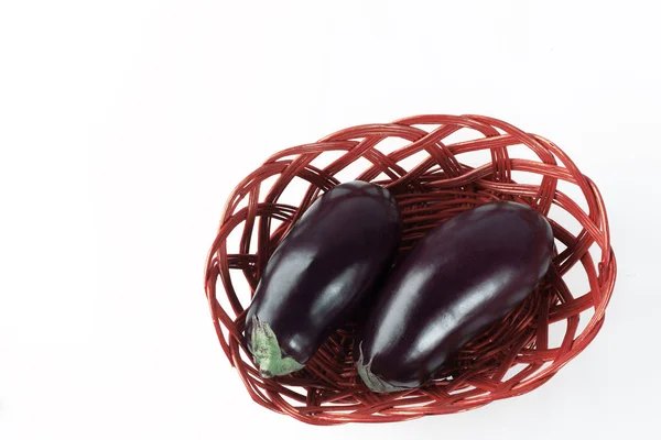 Två mogna aubergine i en korg basket.isolated på vit. — Stockfoto