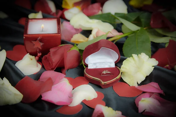 Box s prstenem a okvětními lístky růží v černém hedvábí pozadí — Stock fotografie