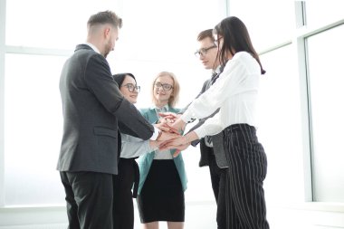 İş adamları ofiste dikilirken birliklerini gösteriyorlar.