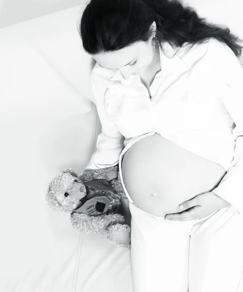 Closeup.Beautiful Kobieta w ciąży z Pluszak, leżąc na kanapie. — Zdjęcie stockowe