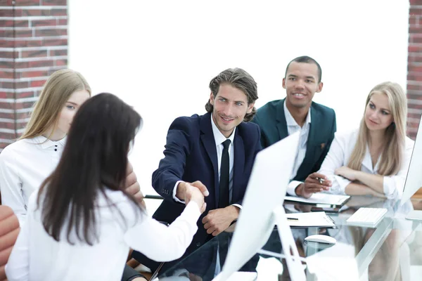 Apretón de manos a las mujeres de negocios con su socio en la mesa de negociaciones — Foto de Stock