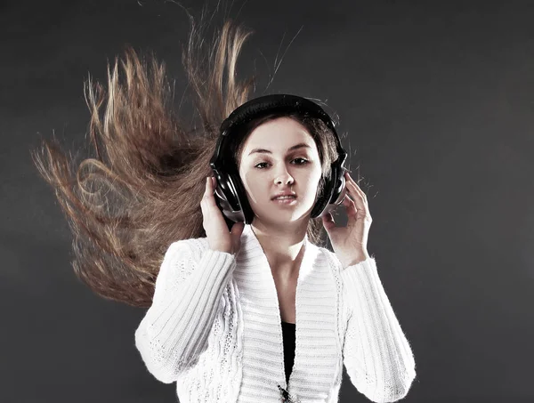 Hermosa mujer joven escuchando música con auriculares .isolated sobre un fondo negro —  Fotos de Stock