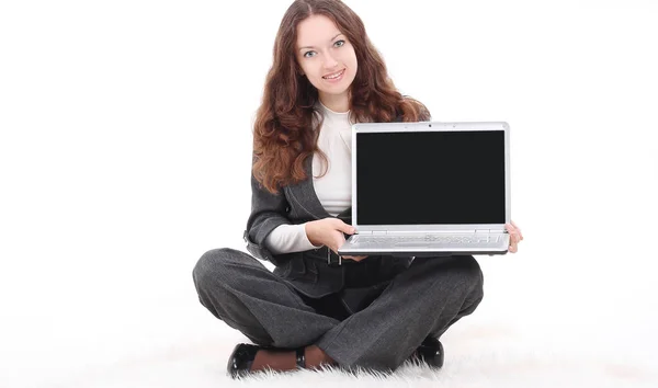 Young business woman showing a laptop sitting on the floor — Stock Photo, Image