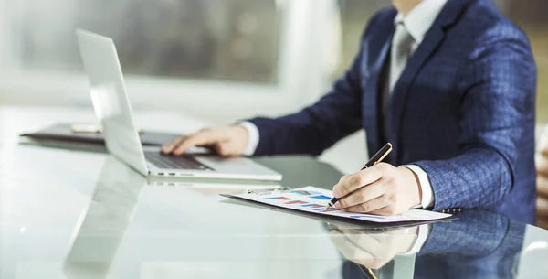 Hombre de negocios exitoso que trabaja en el ordenador portátil con datos financieros en el lugar de trabajo en una oficina moderna. — Foto de Stock