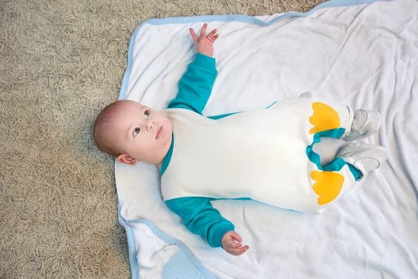 Mignon enfant dans un costume de pingouin couché sur une couverture. — Photo