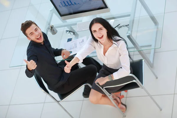 Ansicht von oben. Geschäftspaar sitzt am Schreibtisch und zeigt Daumen hoch — Stockfoto