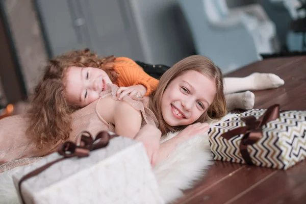 Dos hermosas hermanas tumbadas en el suelo en una acogedora sala de estar — Foto de Stock