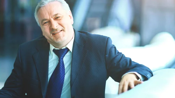 Empresario en la oficina sentado en el sofá sonriendo y mirando el marco —  Fotos de Stock