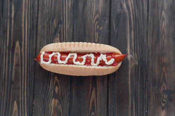 Hot dog s uzenou klobásou a majonézou na dřevěné pozadí — Stock fotografie