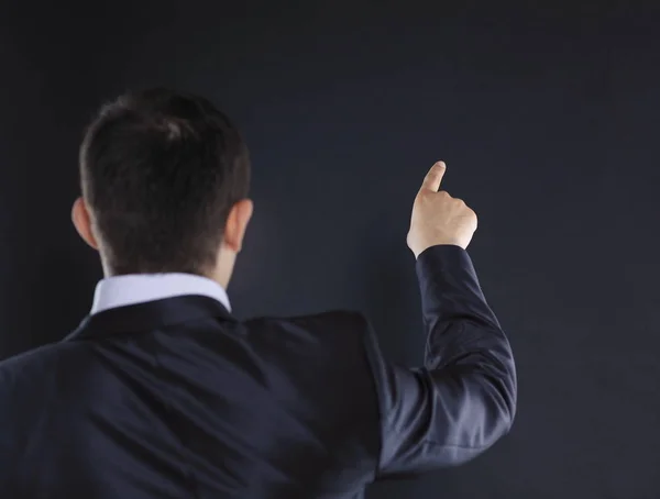Rear view.businessman pointing at copy space.isolated on black — Stock Photo, Image