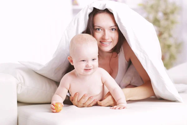 Mom plays with the baby lying on the bed — Stock Photo, Image