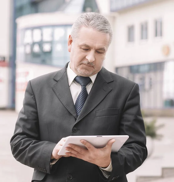 Businessman with digital tablet standing near office building — Stock Photo, Image