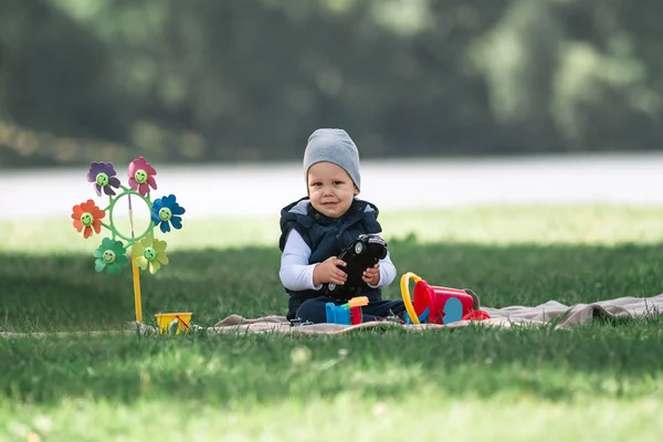 小さな男の子が、公園の芝生の上に座っておもちゃで遊んで — ストック写真