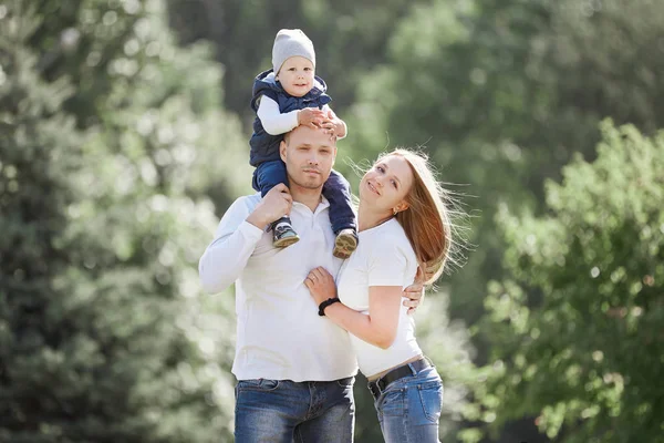 Glückliche Familie mit kleinem Sohn im Hintergrund eines Sommerparks. — Stockfoto