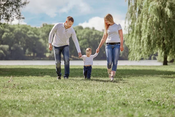 Mutter, Vater und ihr kleiner Sohn spazieren im Sommerpark. — Stockfoto