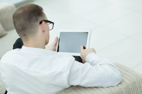 Achteraanzicht. man leest tekst op digitale tablet — Stockfoto