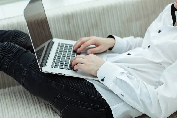 Jonge man kijkend naar laptop scherm liggend op de Bank — Stockfoto