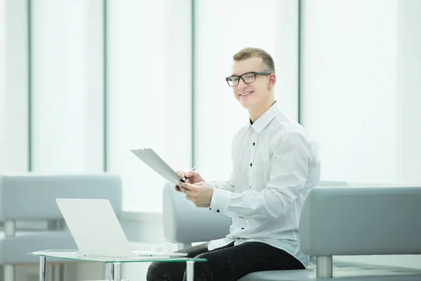 Employé de l'entreprise lit un document d'affaires assis dans le hall du bureau — Photo