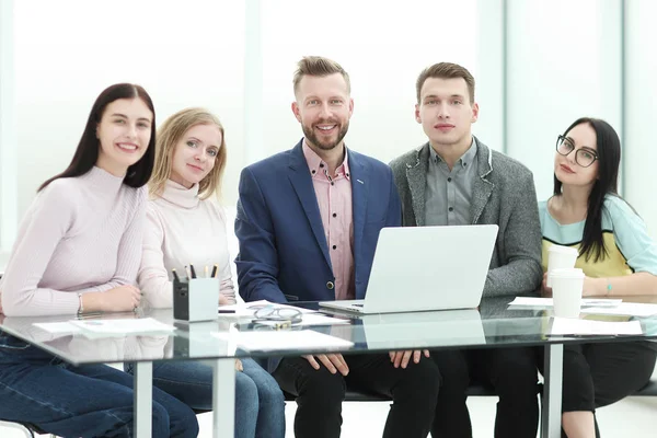 Sonriente equipo de negocios sentado en el escritorio — Foto de Stock