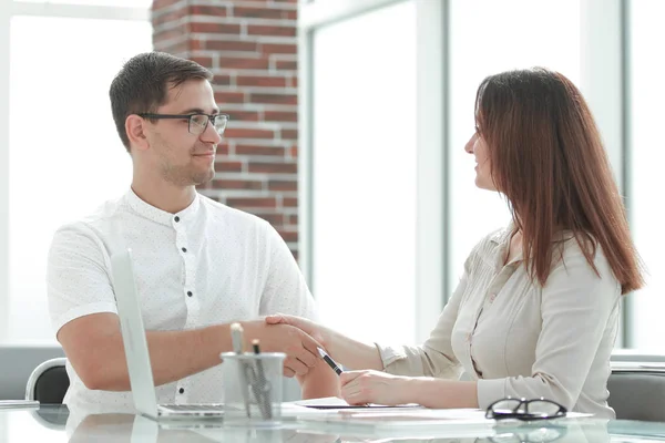 Empresário e empresária apertando as mãos enquanto sentado na mesa . — Fotografia de Stock