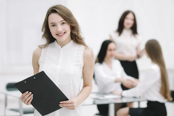 Exitosa joven mujer de negocios con portapapeles en el fondo de la oficina — Foto de Stock