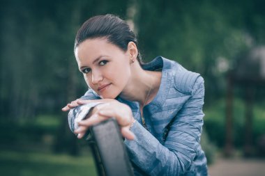 bir bankta oturan sevimli genç kadın