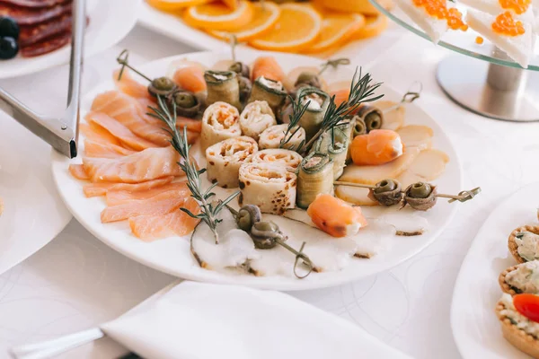 Slices of salmon, rolls of pancakes and mushrooms on a snack plate — Stock Photo, Image