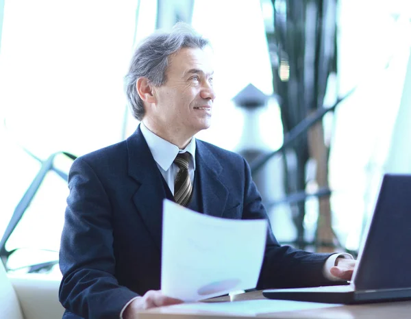 Бізнесмен, який працює з бізнес-документами, сидячи на своєму столі . — стокове фото