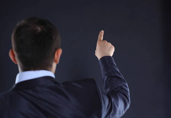 Rear view.businessman pointing at copy space. black background — Stock Photo, Image